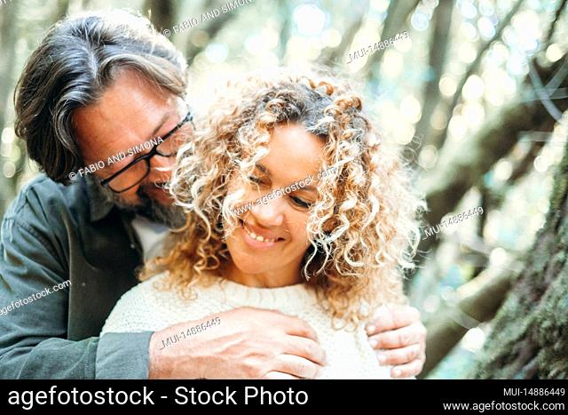 Love and romance in outdoor leisure activity with man and woman in love hugging and bonding outdoors with green trees forest background