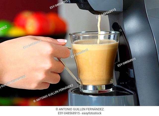 Close up of a woman hand holding a cup in a coffee maker