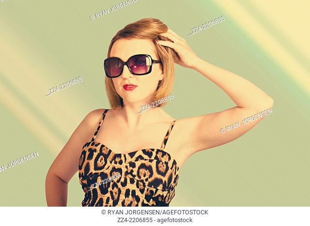 1980 fashion image of a beautiful young sexy pin up woman wearing sunglasses with short auburn hairstyle on green salon background