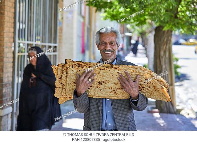 A man walks with freshly baked bread over his arms through the streets of the city of Bijar in western Iran, taken on 04.06.2017. | usage worldwide