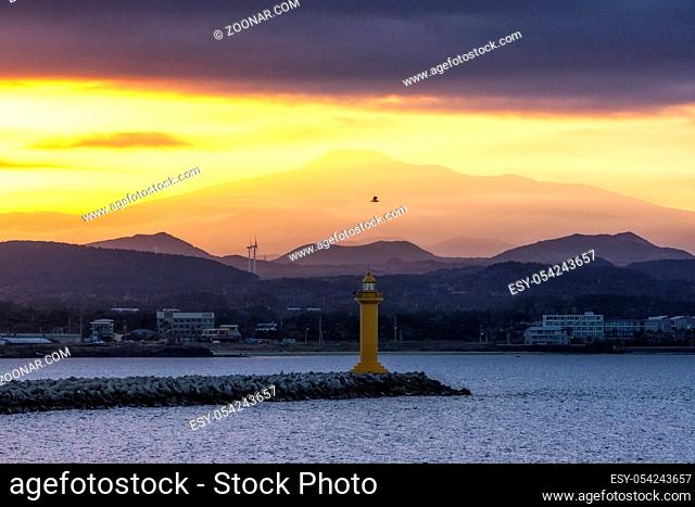 The view of Mount Hallasan with seongsan harbor light house taken from a ferry during sunset hours. Jeju Island, South Korea