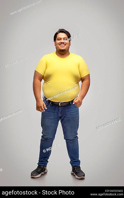 Portrait of a fat man standing and smiling against plain background