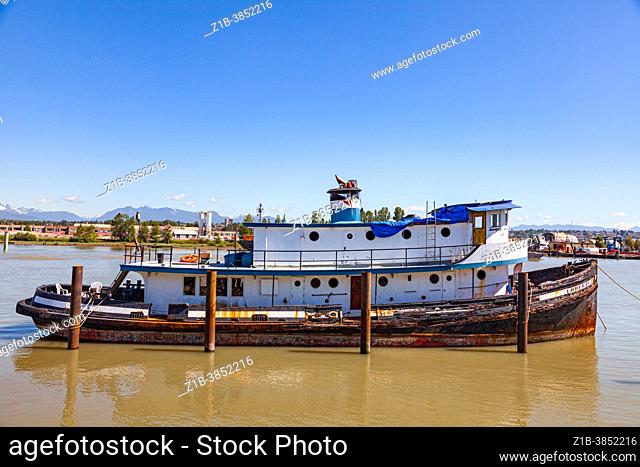 Derelict pleasure boat moored along the shore of the Fraser River in Vancouver British Columbia Canada