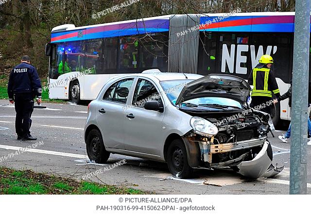 16 March 2019, North Rhine-Westphalia, Mönchengladbach: A policeman stands at an accident scene behind a severely damaged car and in front of a bus