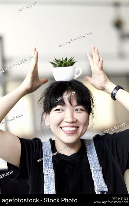 Korean woman holding a cup with leaves on her head