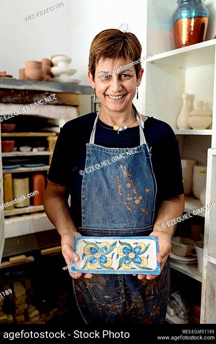 Happy female artist showing her designs at ceramic workshop
