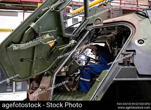 25 July 2023, Hesse, Kassel: A Rheinmetall employee works on a Fuchs tank in Rheinmetall's production hall. Rhein finds out about the company's activities and...