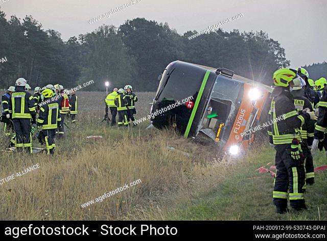 12 September 2020, Mecklenburg-Western Pomerania, Wöbbelin: Firefighters are standing next to a long-distance bus on the A24 motorway
