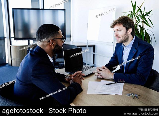 Businessman talking with client at desk in office