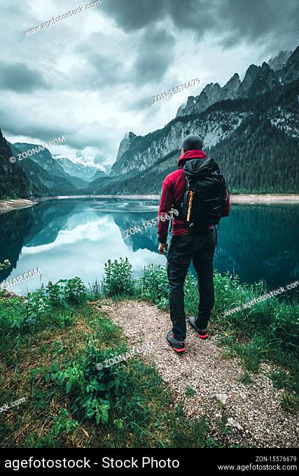 hiker is standing at lake gosau in austria during summer with reflecting mountains in background