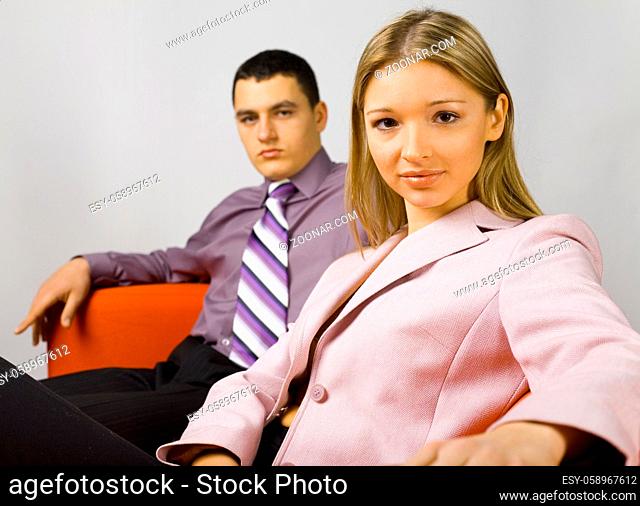 Man and woman sitting on the orange couch. Woman in on the front of camera. Focus on her face
