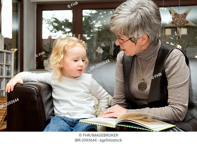 Grandmother reading a book to her granddaughter