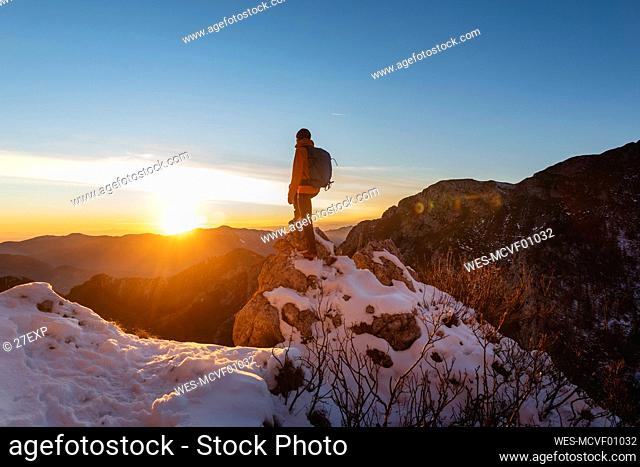 Hiker standing on rock at sunset