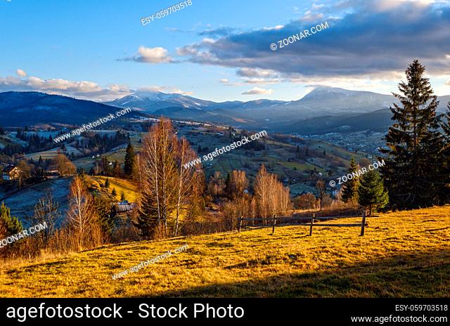 Late autumn mountain pre sunset scene with snow covered tops in far. Picturesque traveling, seasonal, nature and countryside beauty concept scene
