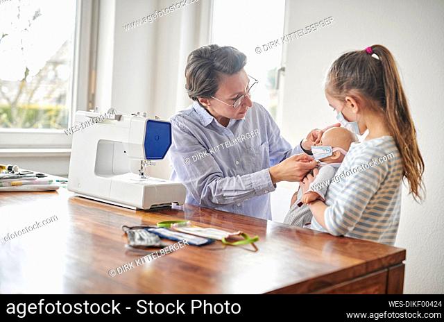 Mother sewing face masks for her daughter and her doll