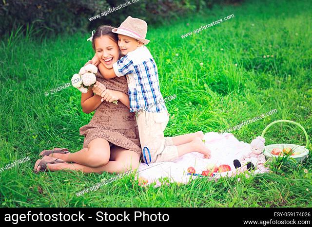 Little boy and teen age girl having picnic on grass. oudoor shot