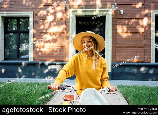 Happy woman standing with bicycle in front of building