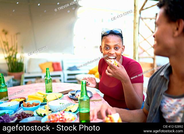 Portrait happy young woman eating taco at patio table