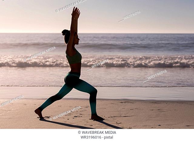 Fit woman performing yoga in the beach