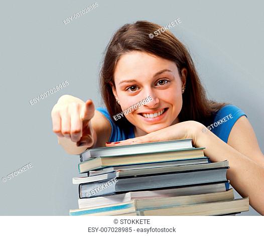 Beautiful young woman with stack of books pointing