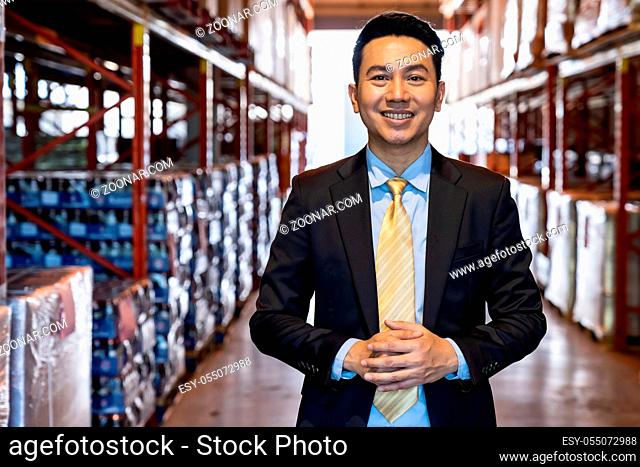 Portrait of asian confidence businessman investor stand in large factory and distribution warehouse environment. Business owner and investment concept