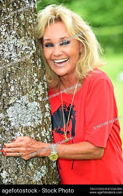 04 June 2021, Bavaria, Gräfelfing: Hella Brice, widow of French actor Pierre Brice, embraces a tree with a smile. June 6 marks the sixth anniversary of the...