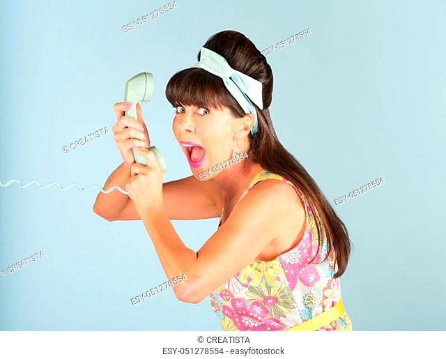 Happy woman in flowery 1950s era dress yelling into a telephone