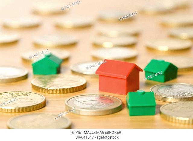 Miniature houses placed between coins
