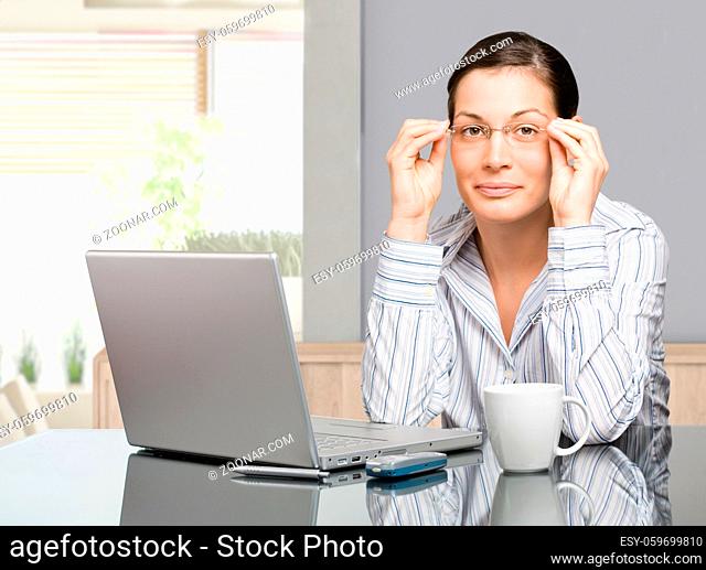 Young woman sitting at desk working with laptop computer at home, smiling