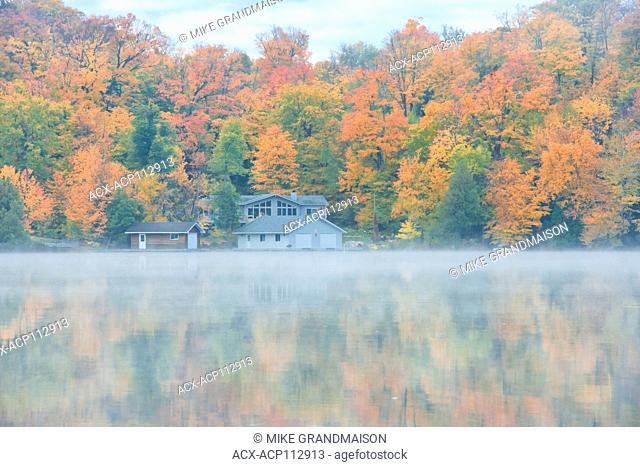 Fog on Horseshoe Lake in autumn with cottage , Near Parry Sound, Ontario, Canada