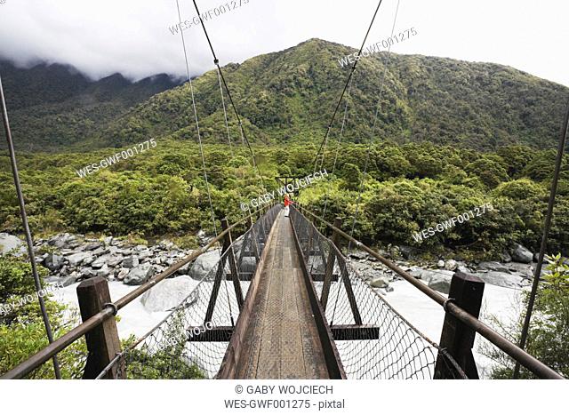 New Zealand, South Island, Woman crossing fox river through swing bridge