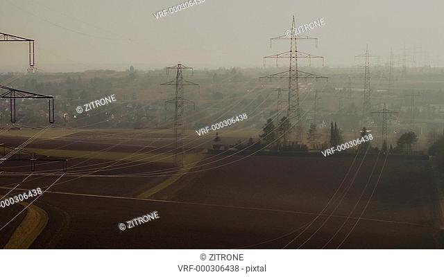 Drone shot of electricity pylons in field near town, Stuttgart, Baden-Wuerttemberg, Germany