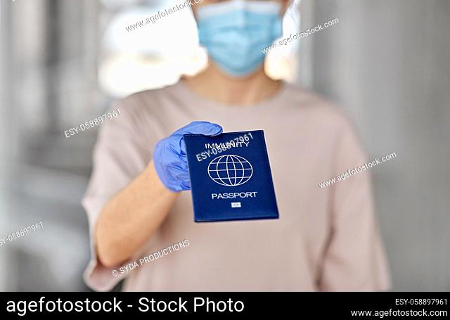 woman in mask and gloves holding immunity passport