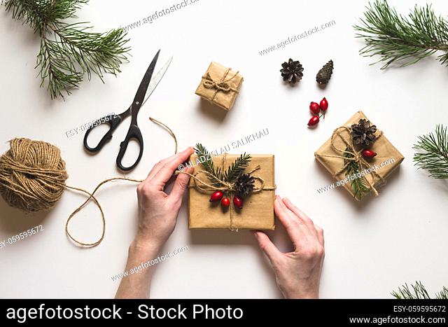 Christmas composition. Female hands keeping christmas gifts, pine branches, toys on white background. Flat lay, top view, copy space