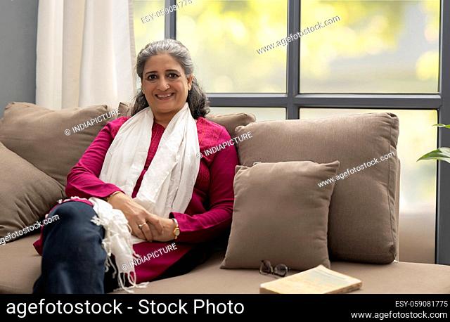 A HAPPY SENIOR ADULT WOMAN SITTING AND LOOKING AT CAMERA