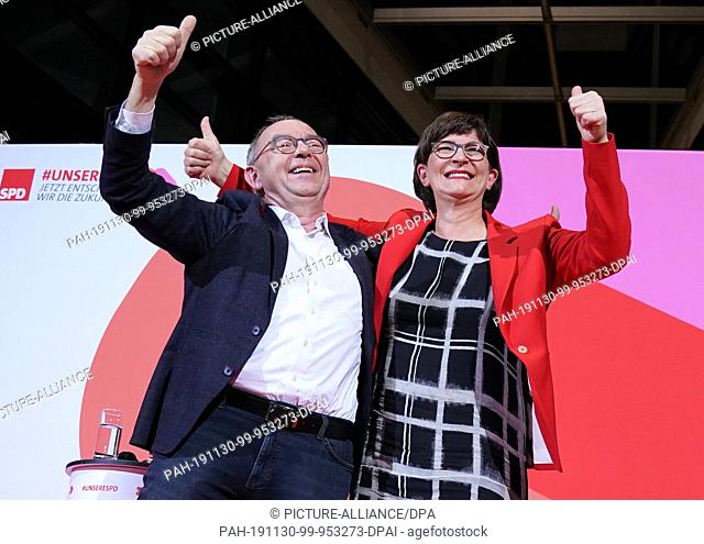 30 November 2019, Berlin: Norbert Walter-Borjans and Saskia Esken wave after the announcement of the result of the vote on the SPD chairmanship in the Willy...