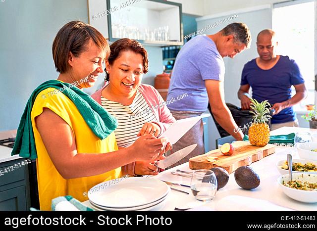 Happy couple friends using digital tablet and cooking in kitchen