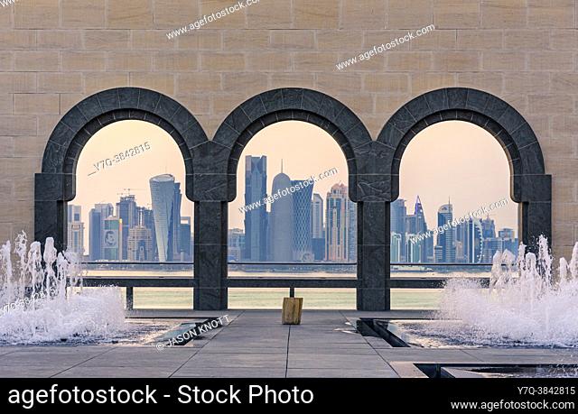 Doha city skyline views at sunset through the arches of the courtyard at the Museum of Islamic Art, Doha, Qatar
