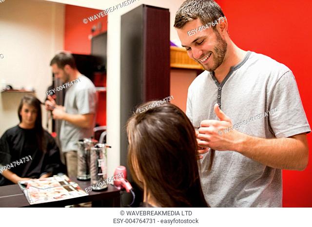 Smiling male hairdresser cutting hair