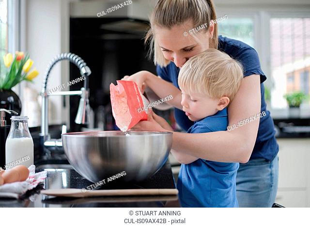 Mother helping son bake cake