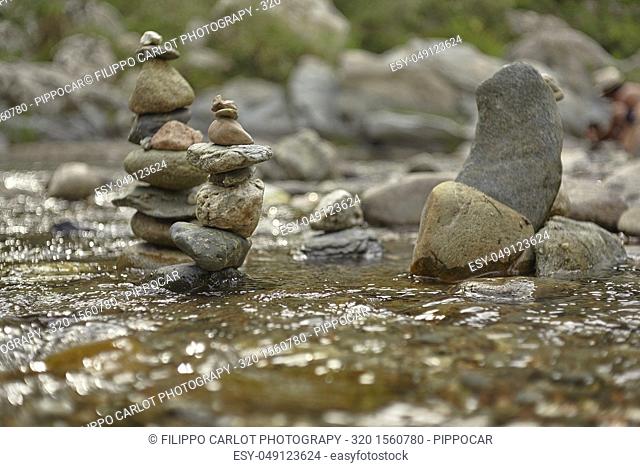 Stacks of rocks and pebbles in the middle of the flowing of a stream in the natural dripper of Sa Stiddiosa in Sardinia
