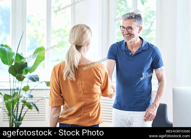Happy doctor shaking hands with patient in medical practice