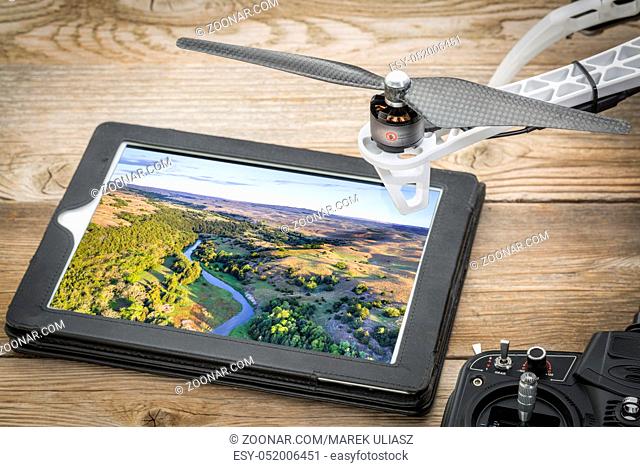 aerial photography concept - reviewing pictures of the Dismal RIver in Nebsrask on a digital tablet with a drone rotor and radio controller