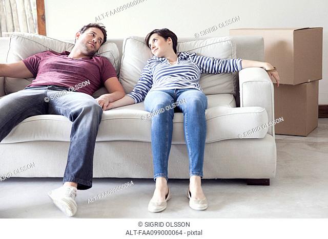 Couple relaxing on sofa while moving house