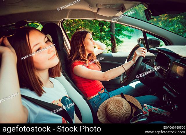 Two young girls driving in car, enjoy summer road trip in nature