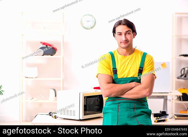 The young repairman repairing microwave in service centre
