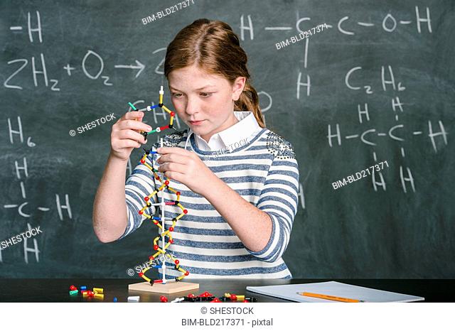Caucasian student examining molecular model in science class