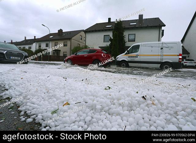26 August 2023, Bavaria, Augsburg: Hail lies on a sidewalk and drifts on a flooded street. Thunderstorms with strong winds and hail caused numerous operations...
