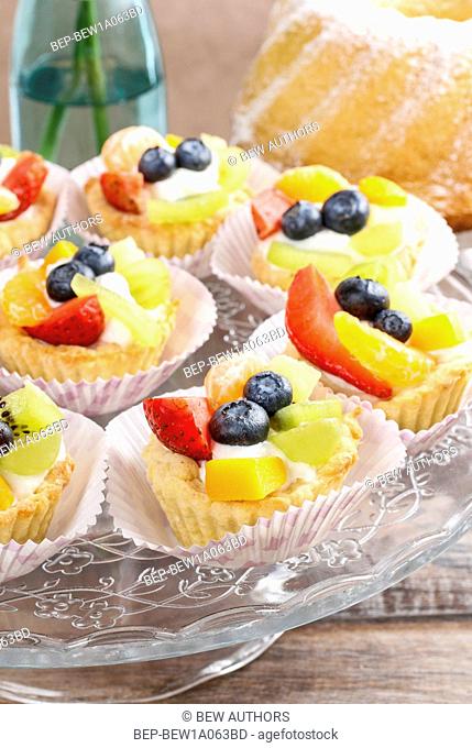 Cupcakes with cram and fresh fruits: strawberry, peach, kiwi, blueberry