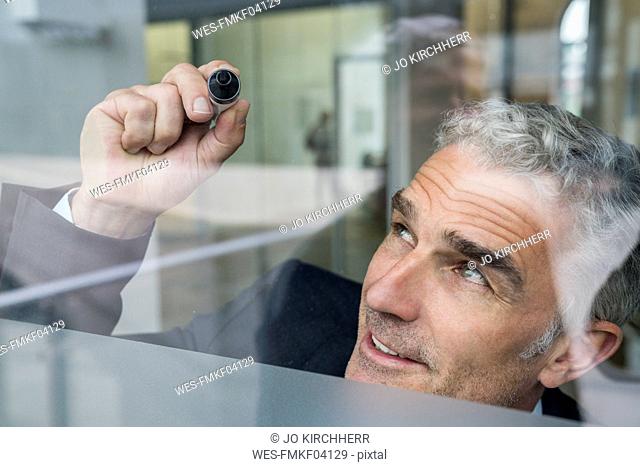 Mature businessman looking writing on glass pane